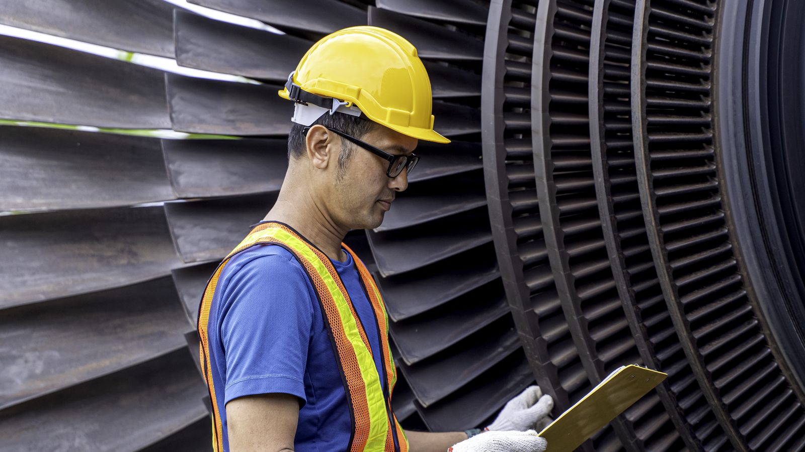Technician reviews a checklist next to a steam turbine.