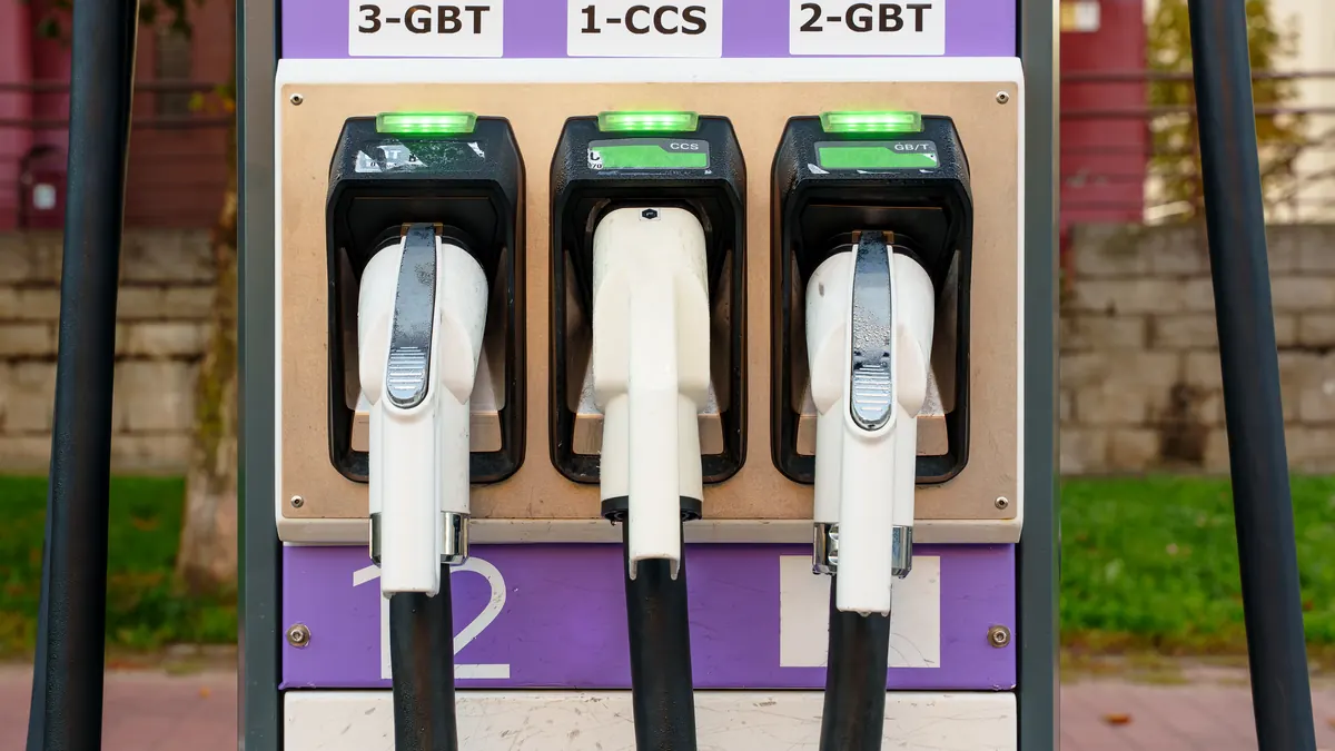 Three electric vehicle charging connectors on a dispenser.