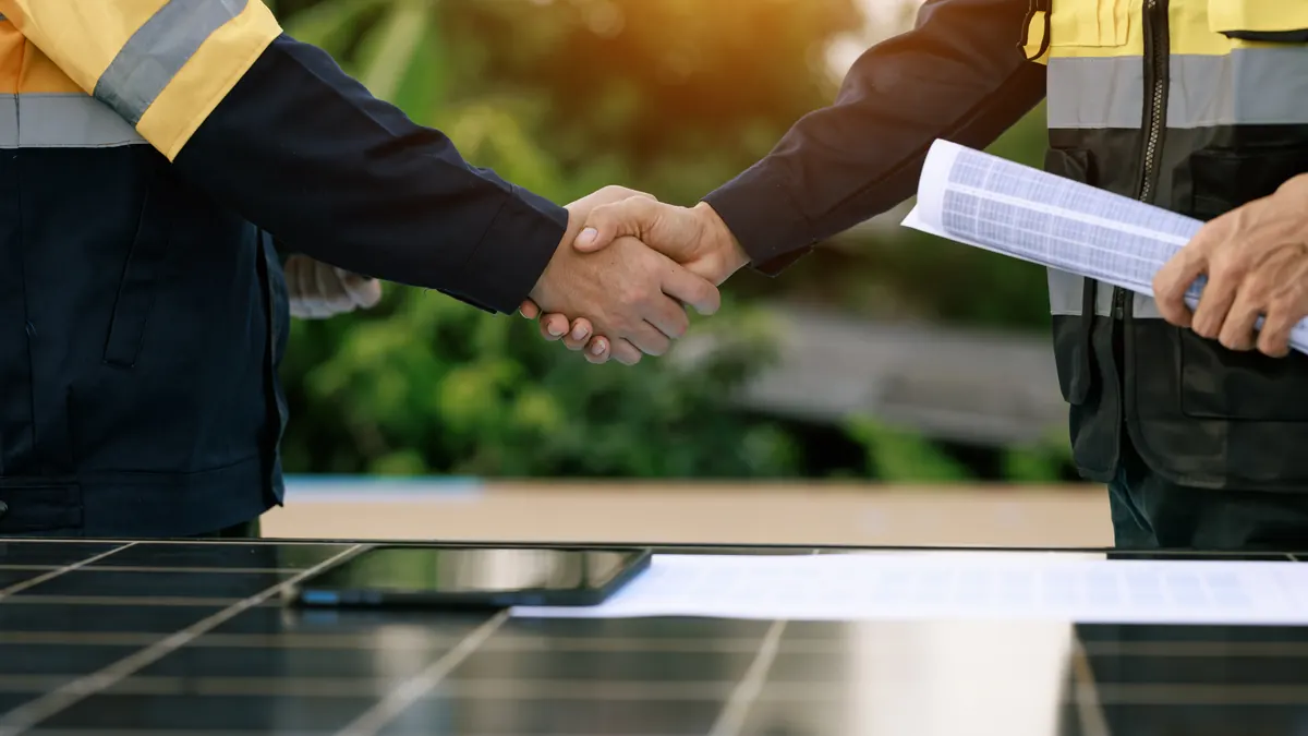 Handshake over a solar array when closing a deal.