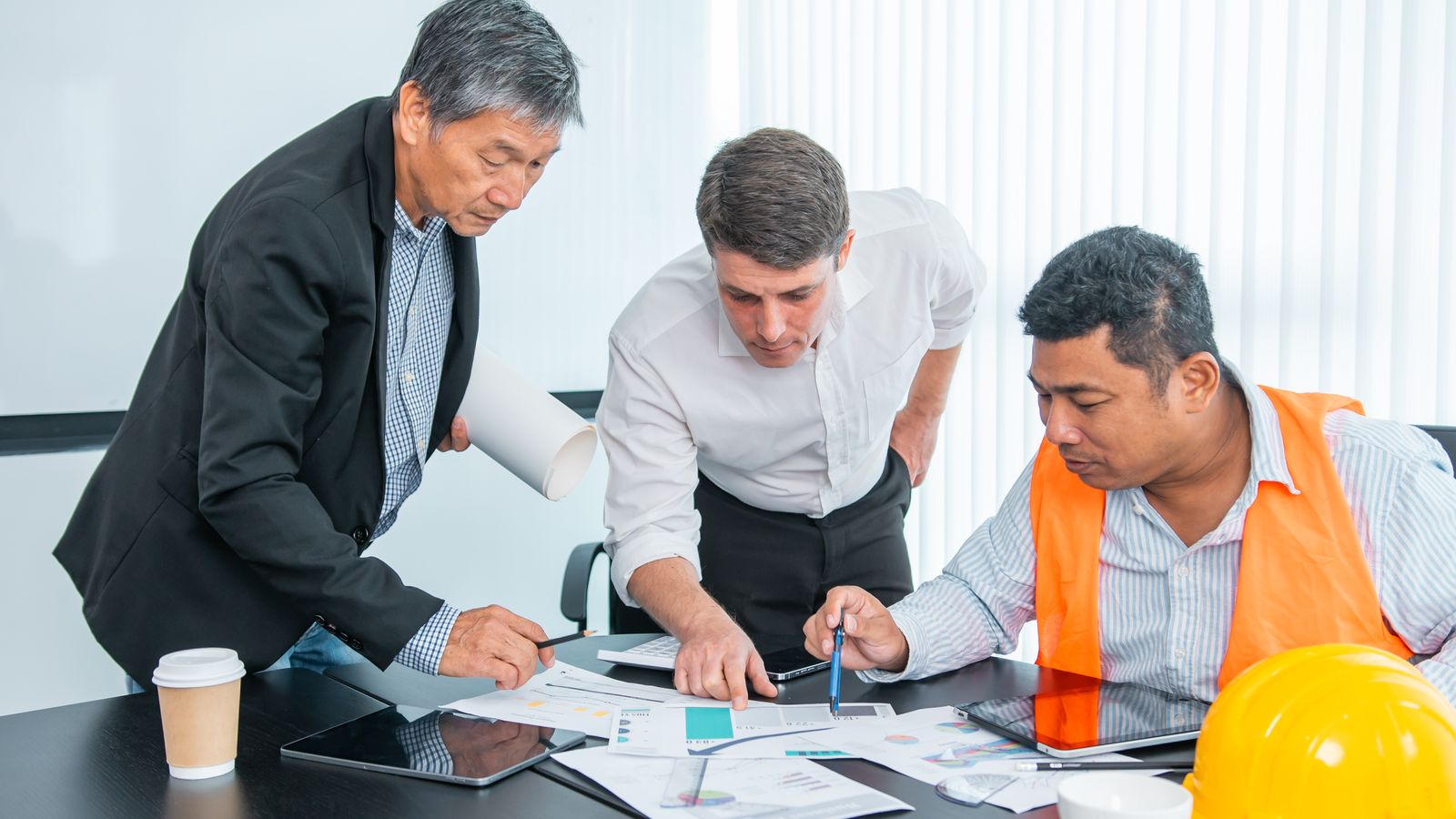 Management team reviews drawings and a proposal in a meeting room.