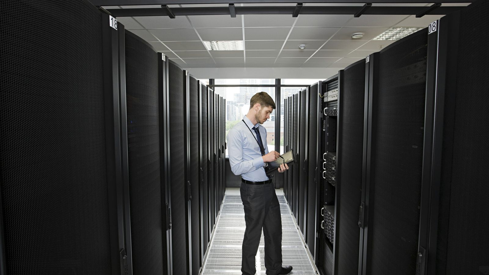 Technician inspects a rack aisle in a data center.