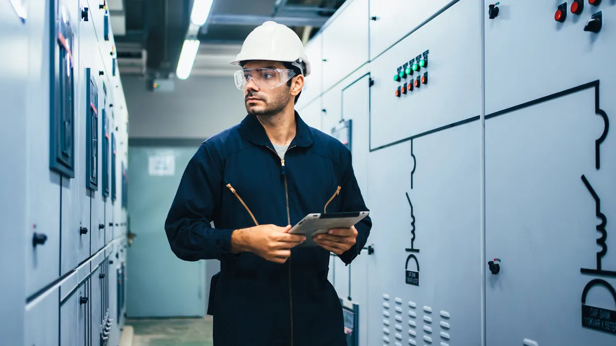 Engineer inspects medium-voltage switchgear with a tablet.