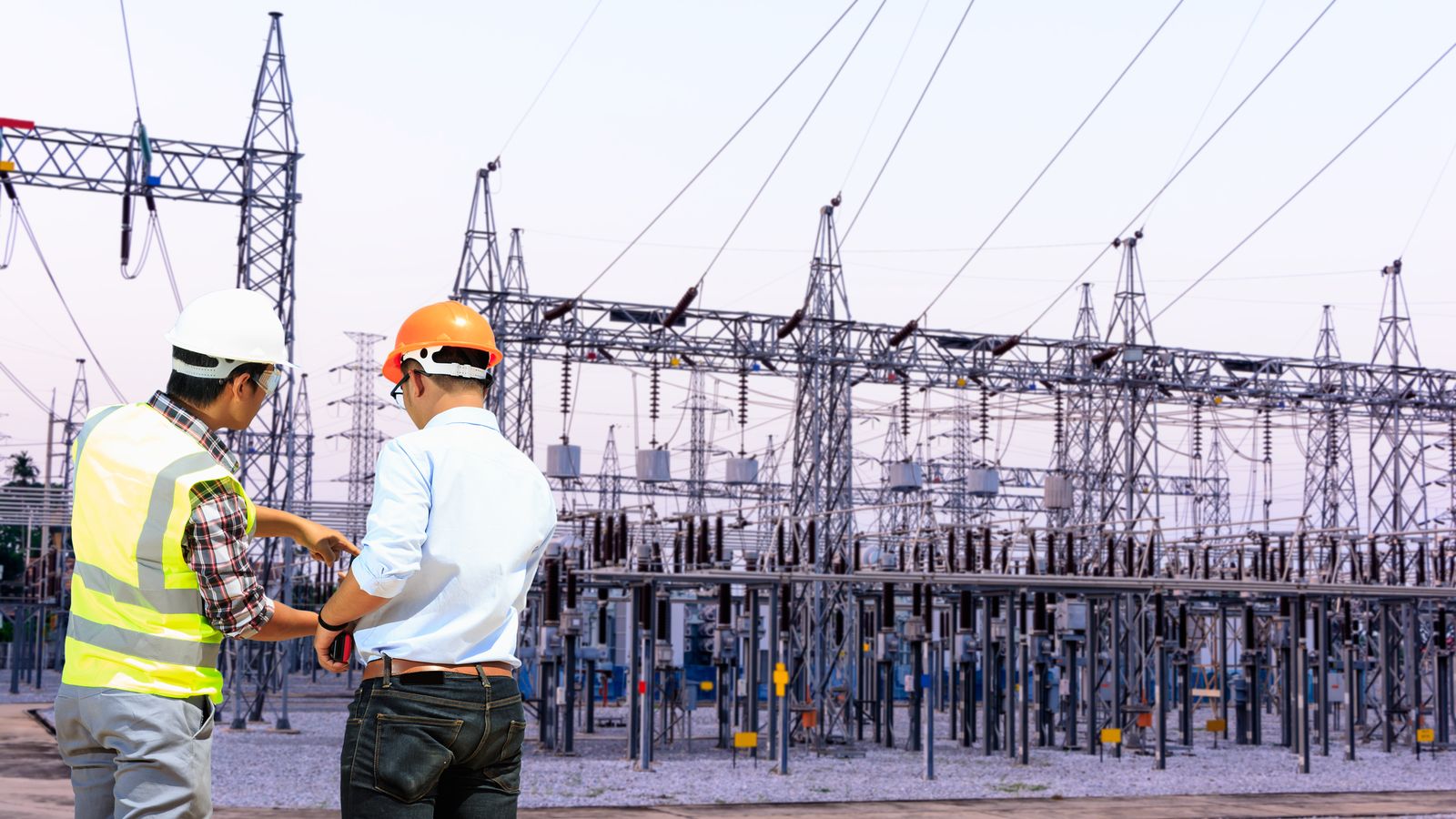 Engineers review documents in front of a substation.