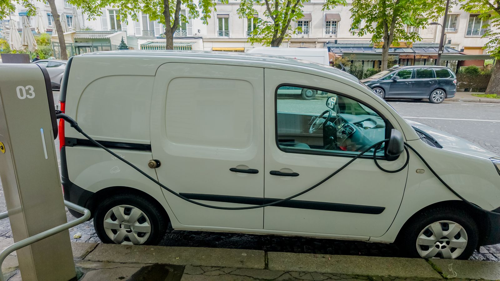 Electric delivery van plugged into a charger.