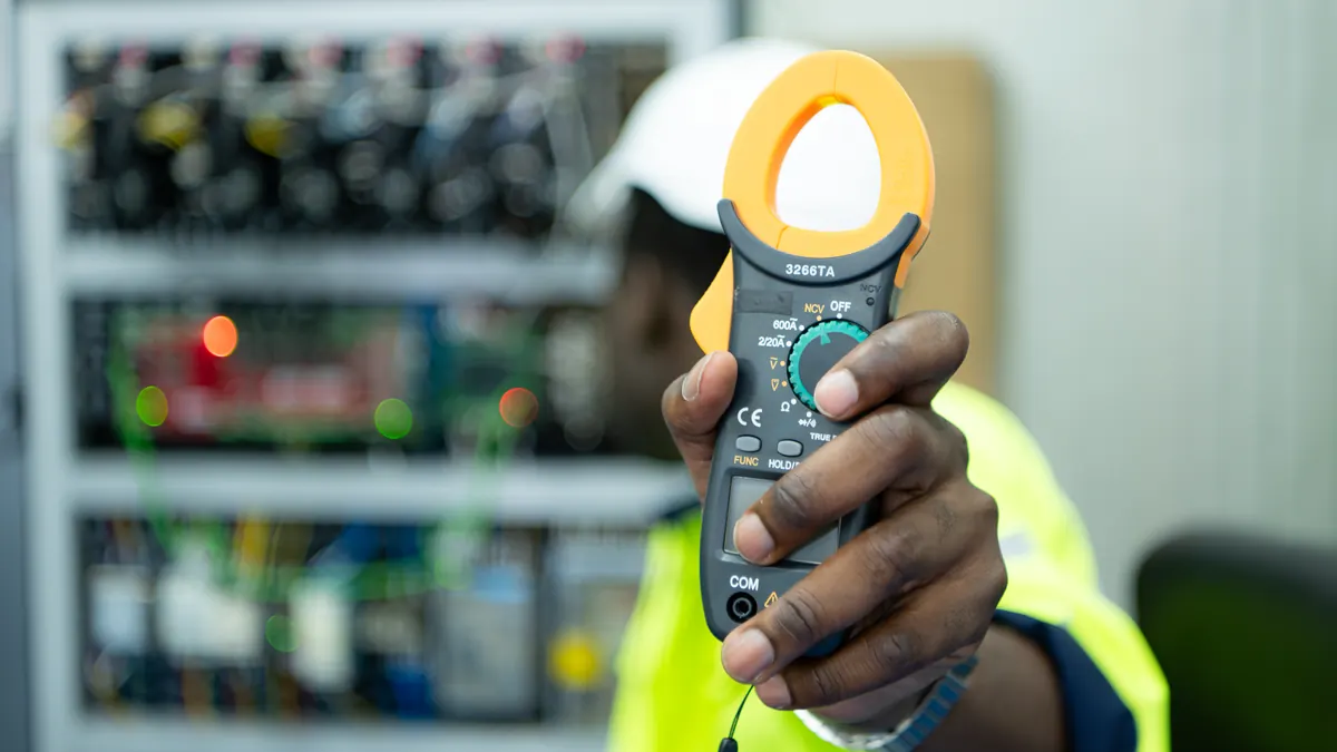 Technician measures current with a clamp meter at a switchboard.