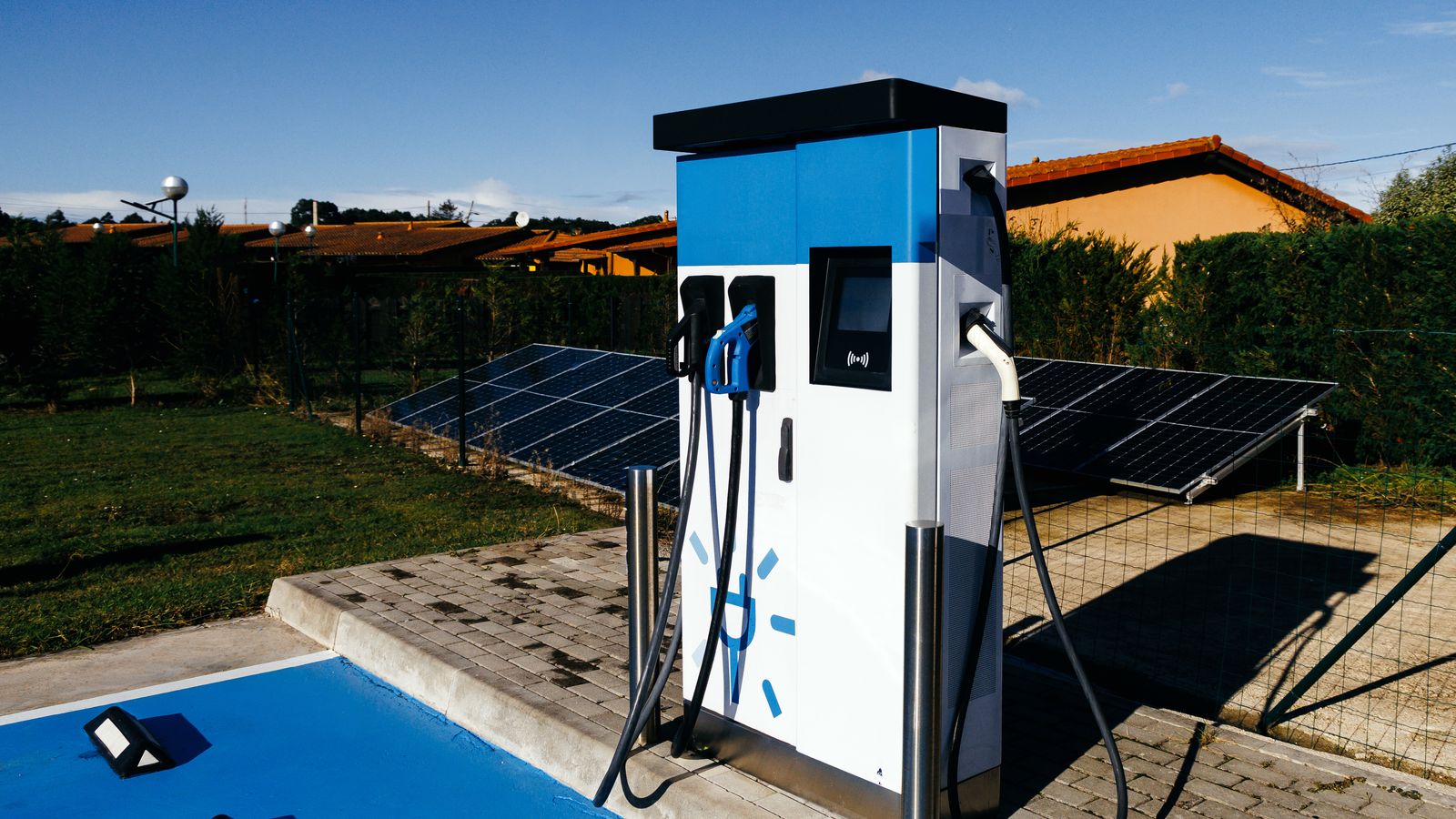 Estación de carga de vehículos eléctricos junto a un arreglo de paneles solares.